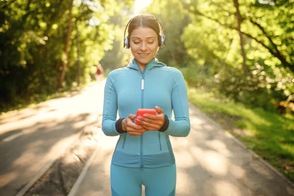 runner starting a running playlist on her phone to listen to music